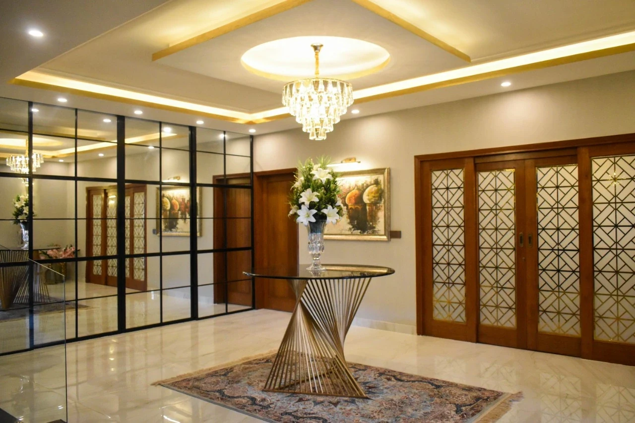 Wide foyer with gold pedestal table and screens.