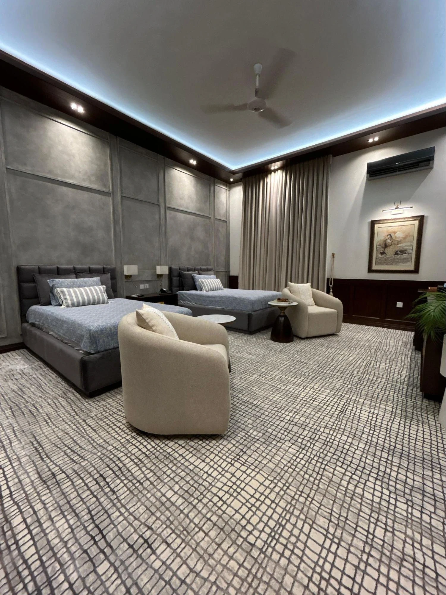 Renovated twin bedroom with upholstered beds and chairs.